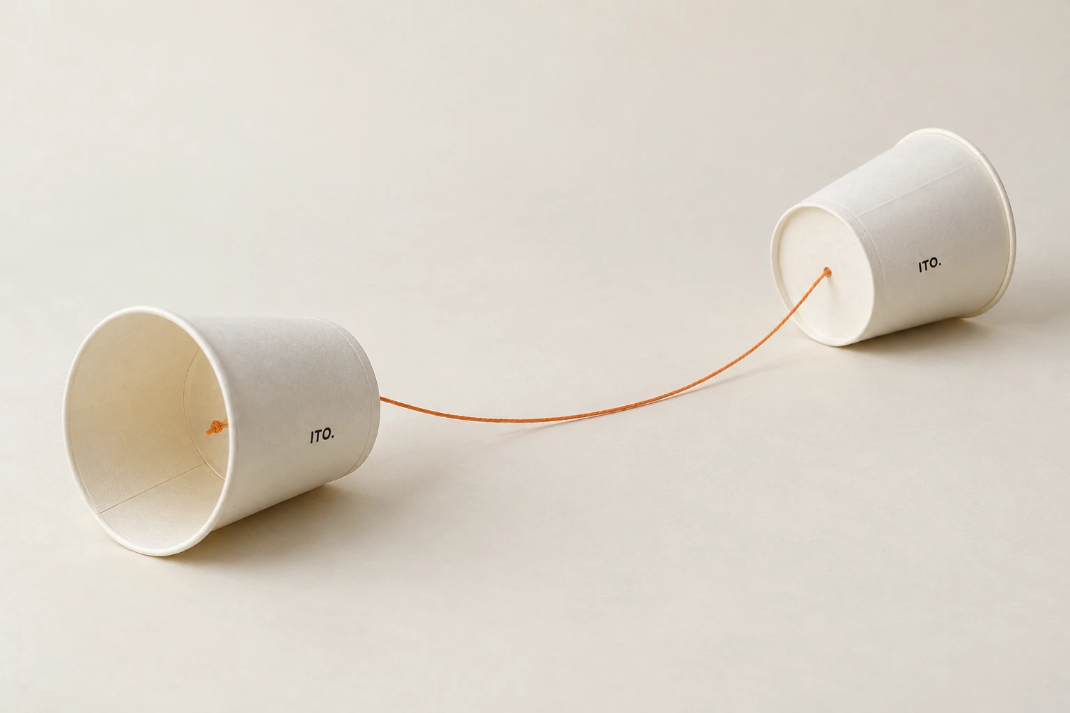 底の小さな穴にオレンジの糸を通して結んだ、白い紙コップ2個の手作り糸電話